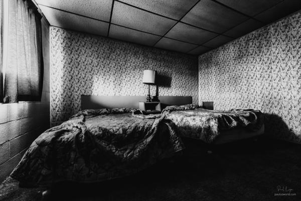 Black and white photo of an untouched room in an abandoned motel.